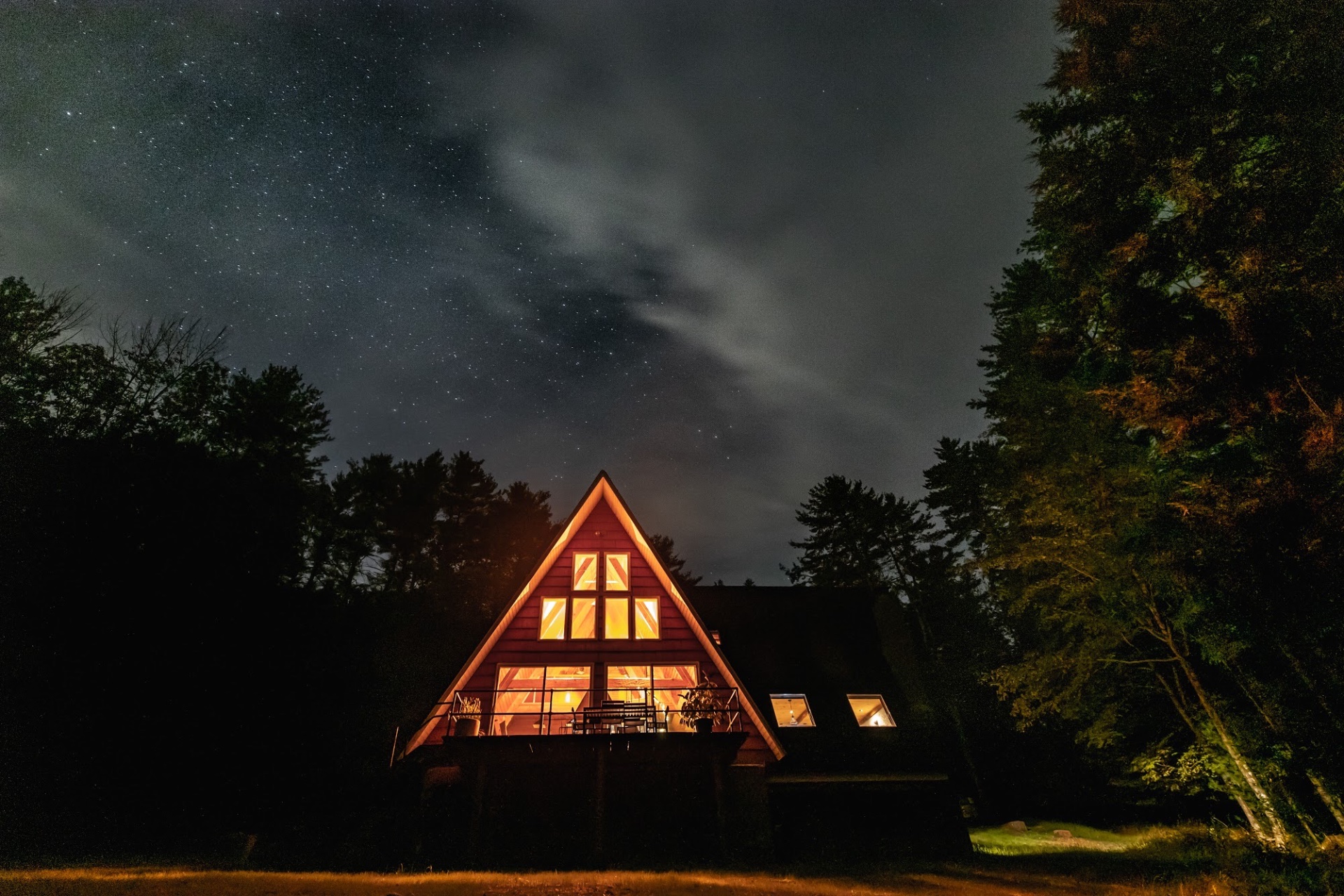 A hand-built A-frame cabin glowing at dusk in the Catskills forest
